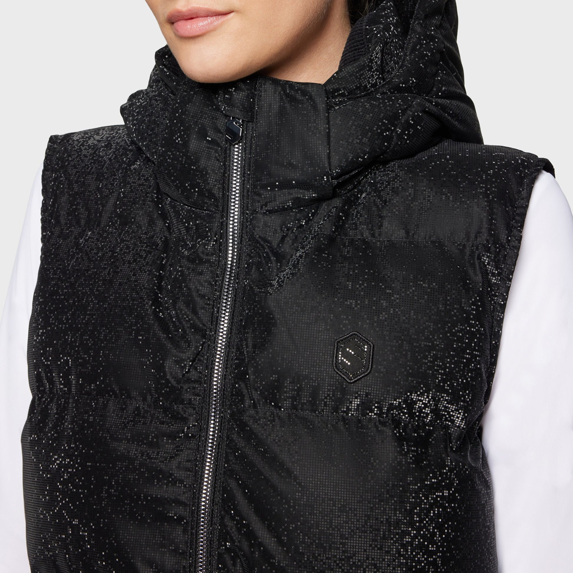 Black puffer vest with glittery texture worn by a person on a white background