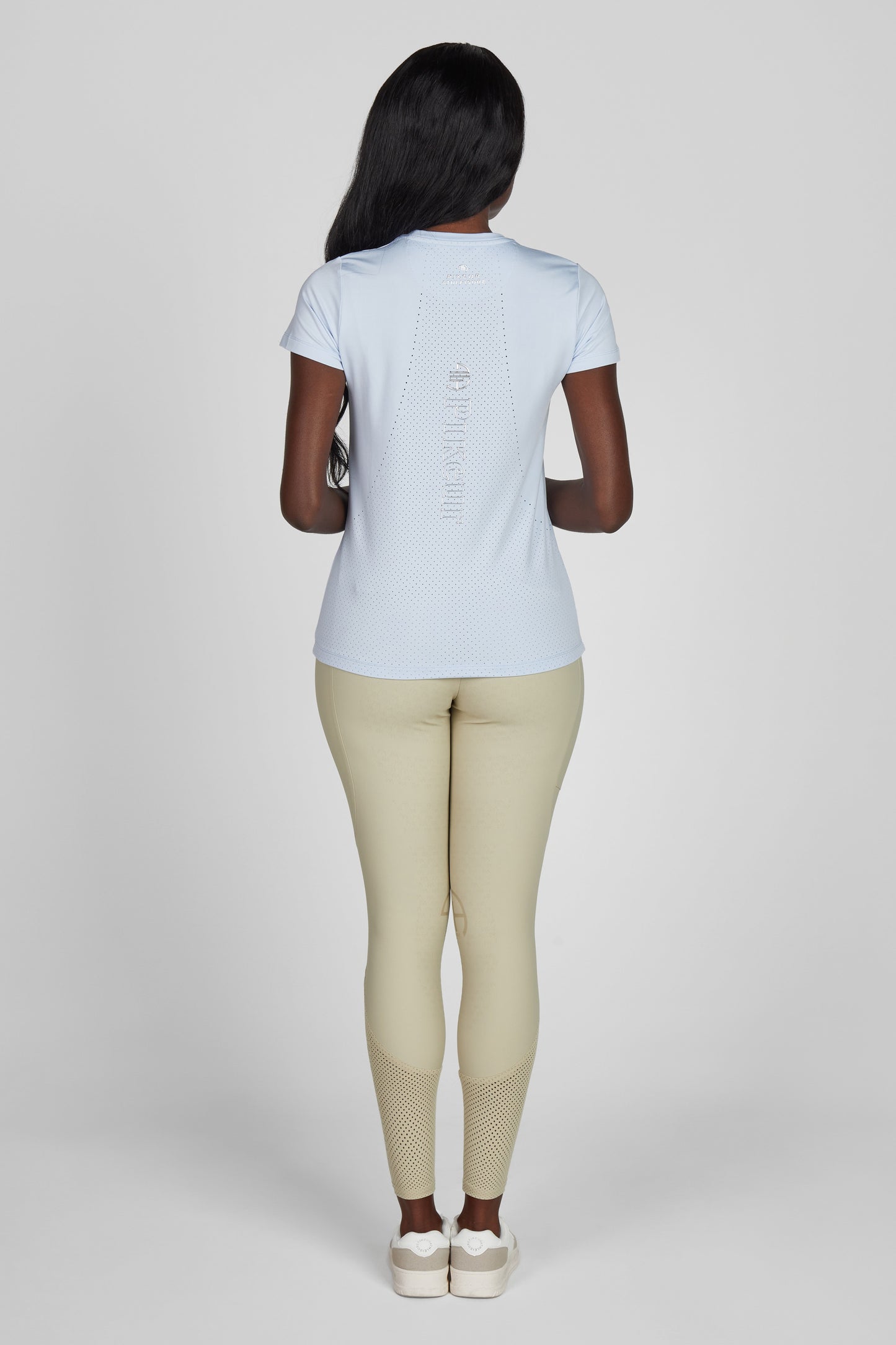 Model wearing a blue t shirt and a pair of beige breeches on a grey background