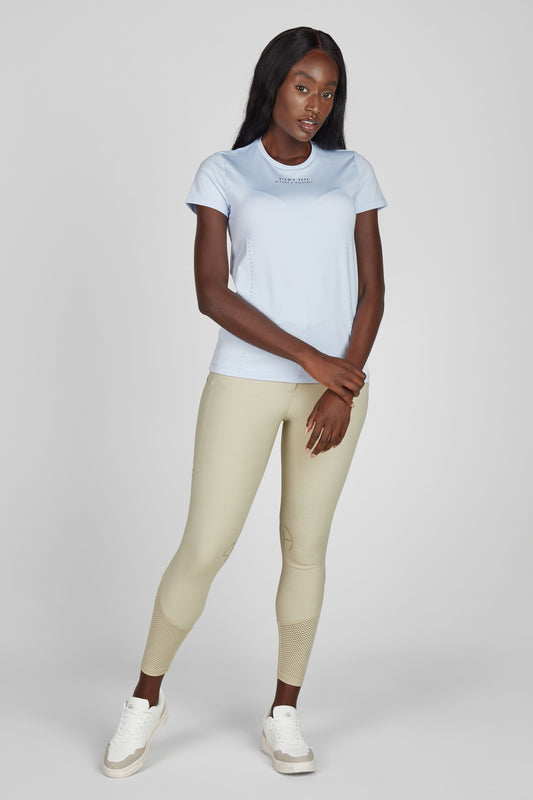Model wearing a blue t shirt and a pair of beige breeches on a grey background