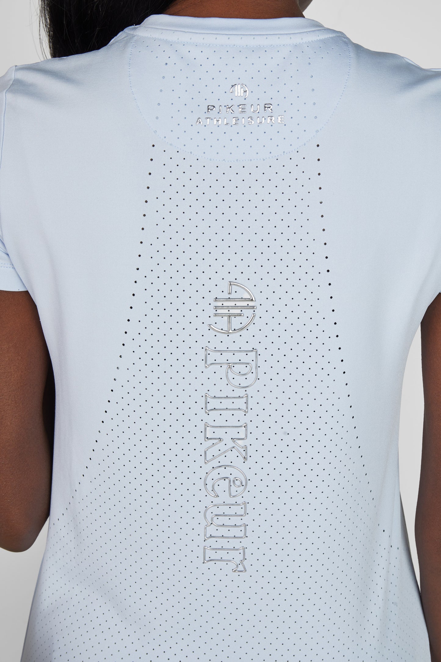 Close up of the back of a blue t shirt with perforations and the Pikeur logo