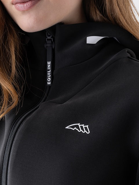 A woman wearing a black zip-up hooded jacket with white reflective-looking trim details on the hood, cuffs, and hem, against a plain light gray studio background.