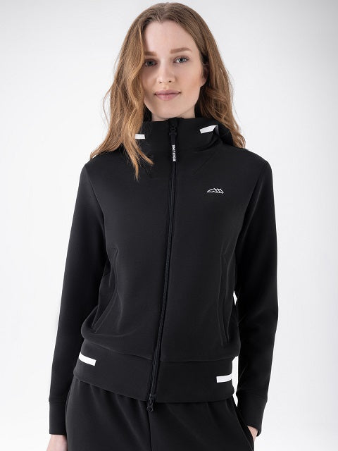 A woman wearing a black zip-up hooded jacket with white reflective-looking trim details on the hood, cuffs, and hem, against a plain light gray studio background.