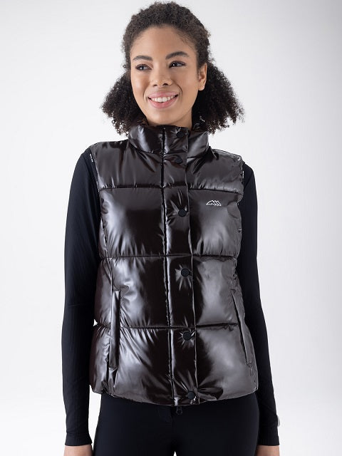 A woman wearing a shiny quilted puffer vest over a black long-sleeve shirt, photographed against a light gray studio background.