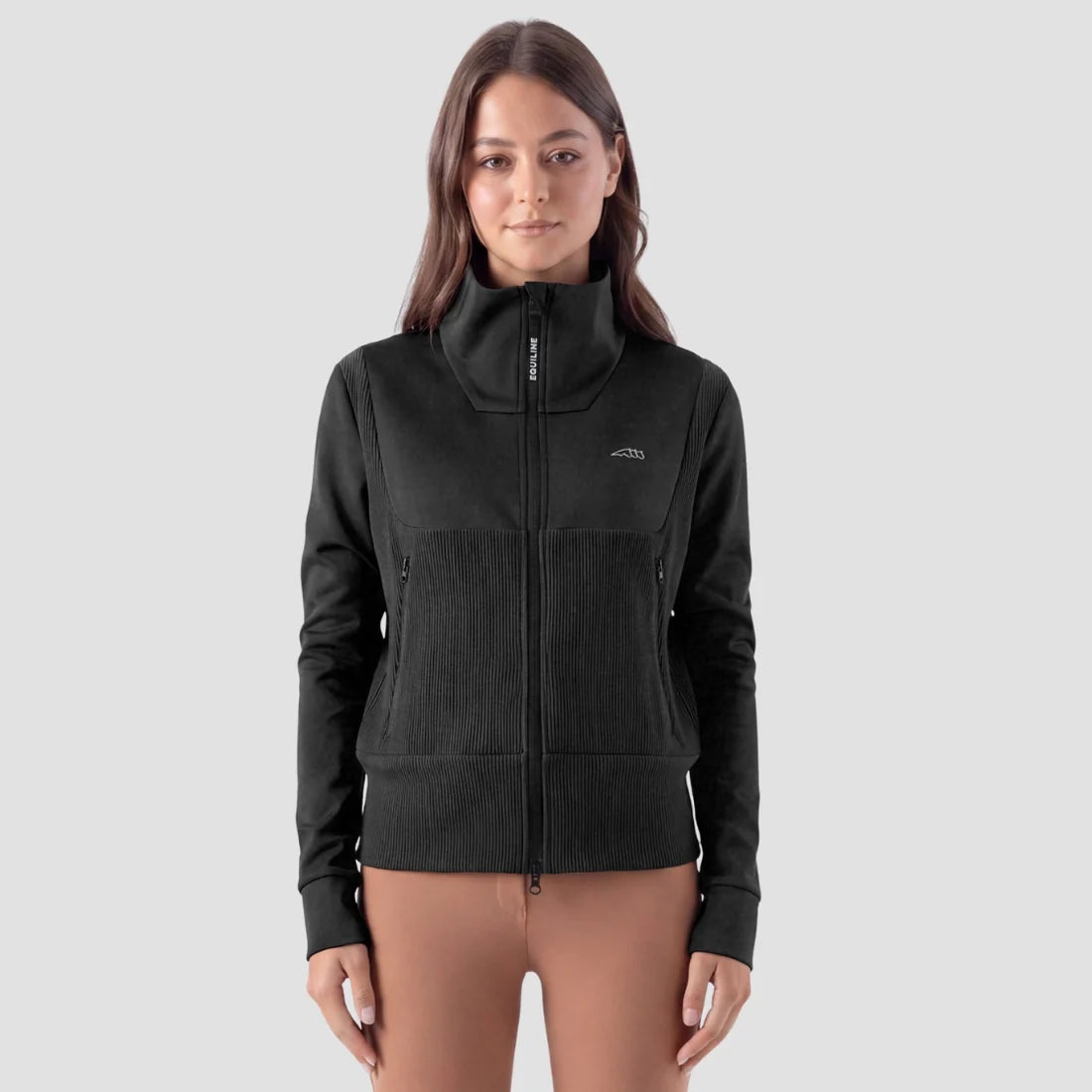 A woman modeling a black full-zip fleece jacket with a stand-up collar and zippered hand pockets, paired with brown leggings, against a light gray studio background.