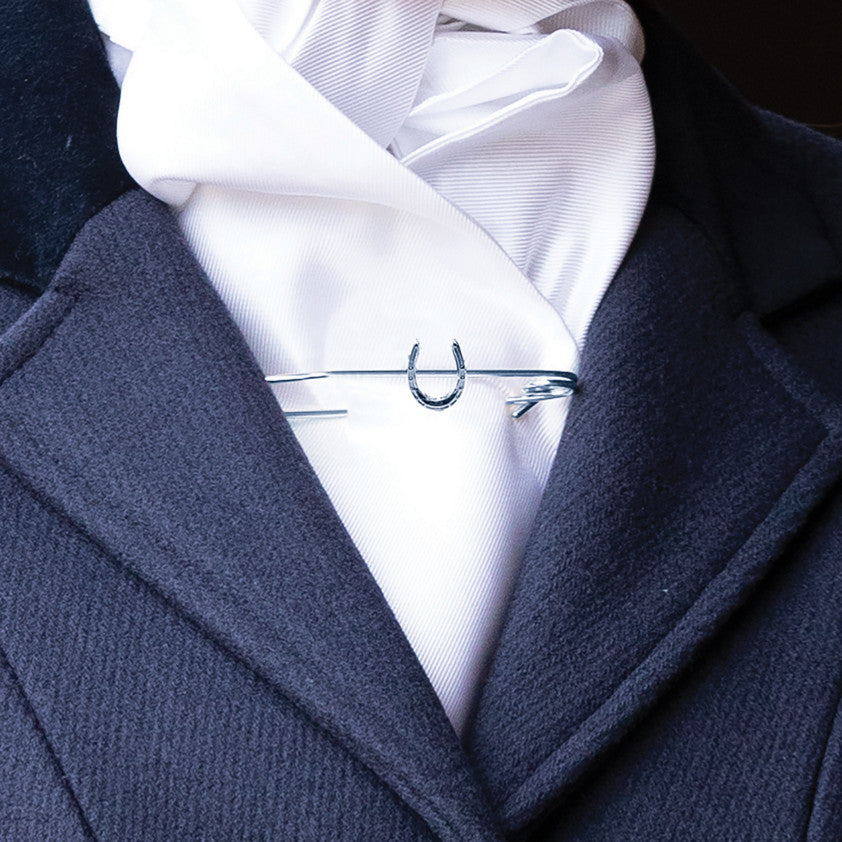 Navy coat over a white shirt with a tie and silver stock pin.