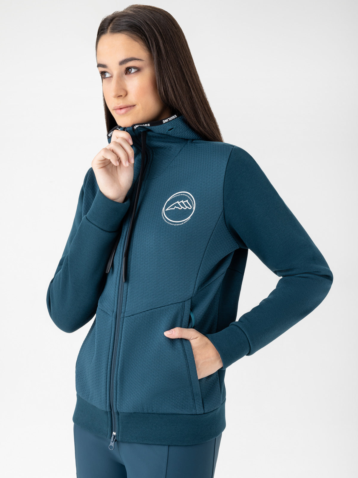 Woman wearing a teal sweatshirt with an Equiline logo on a white background