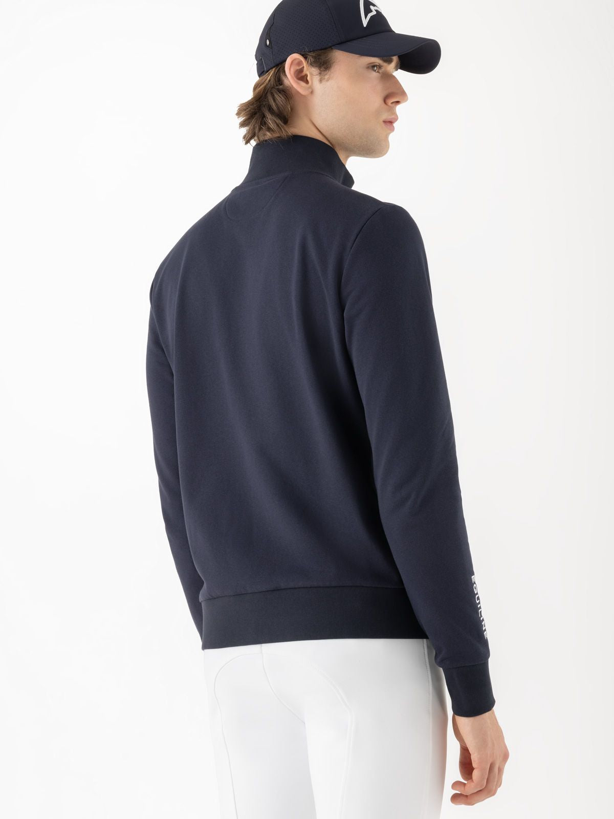 Man wearing a navy blue jacket and cap on a white background