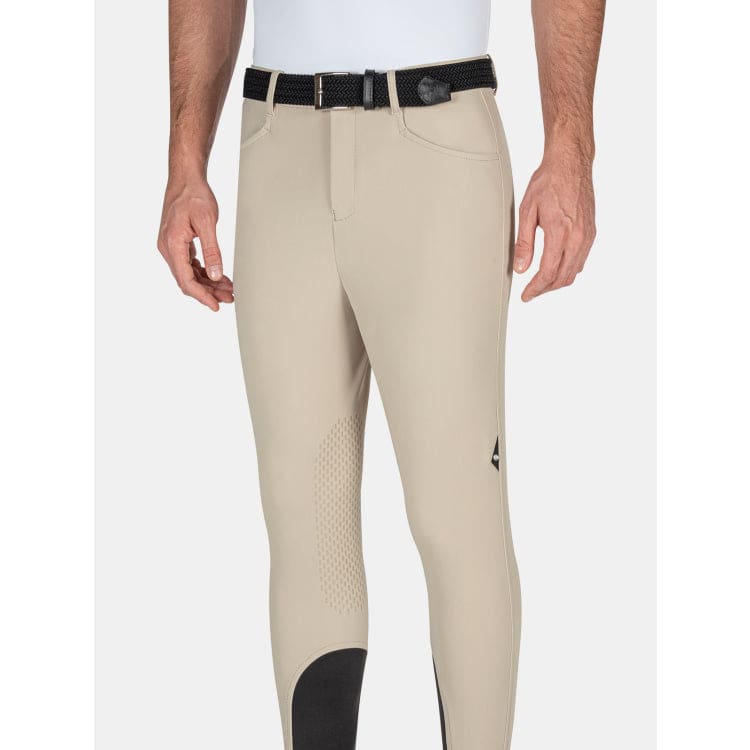 man wearing beige equiline breeches with logo on a white background