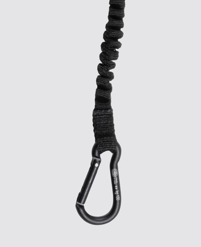 A close-up of a black elastic bungee cord with a black metal carabiner, shown vertically against a solid light gray background.