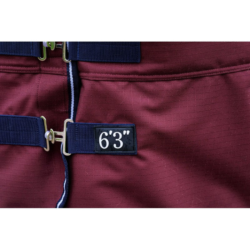 Close-up of a burgundy rug with navy blue adjustable straps and metal buckles, featuring a black fabric patch with white text reading '6'3"'.