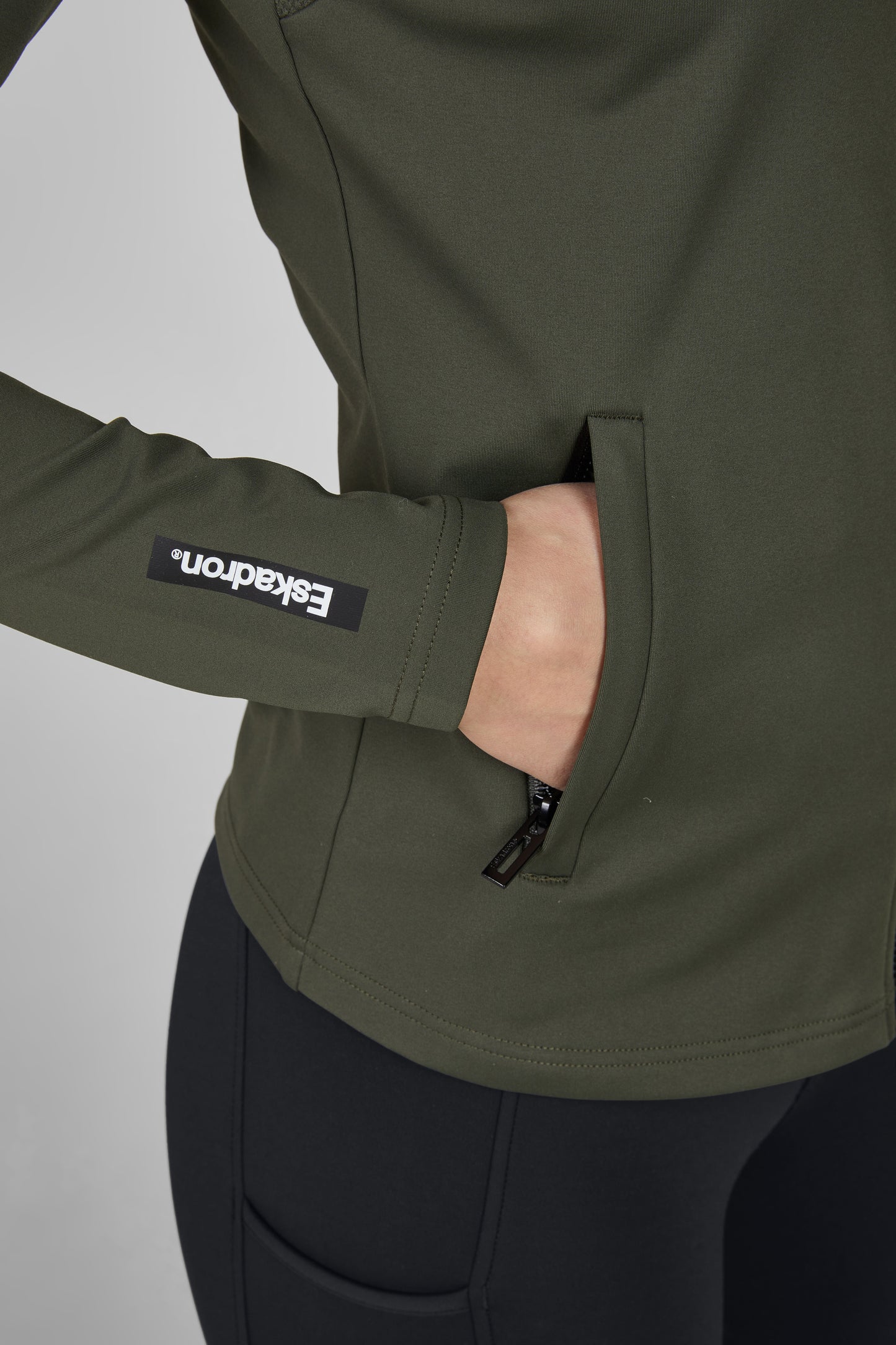 Green jacket with a brand logo on the sleeve against a gray background