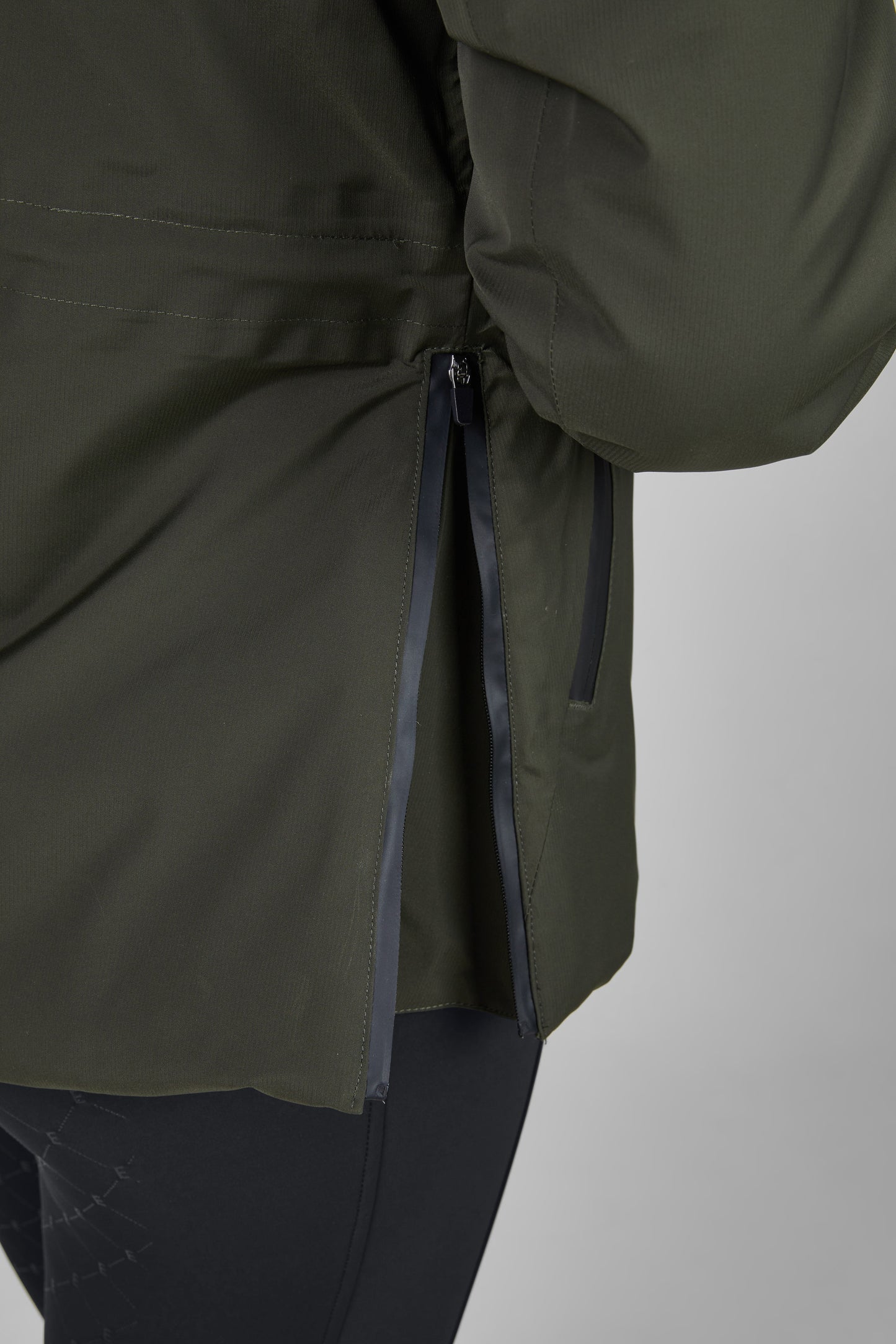 Close-up of a green jacket with a zipper on a light gray background