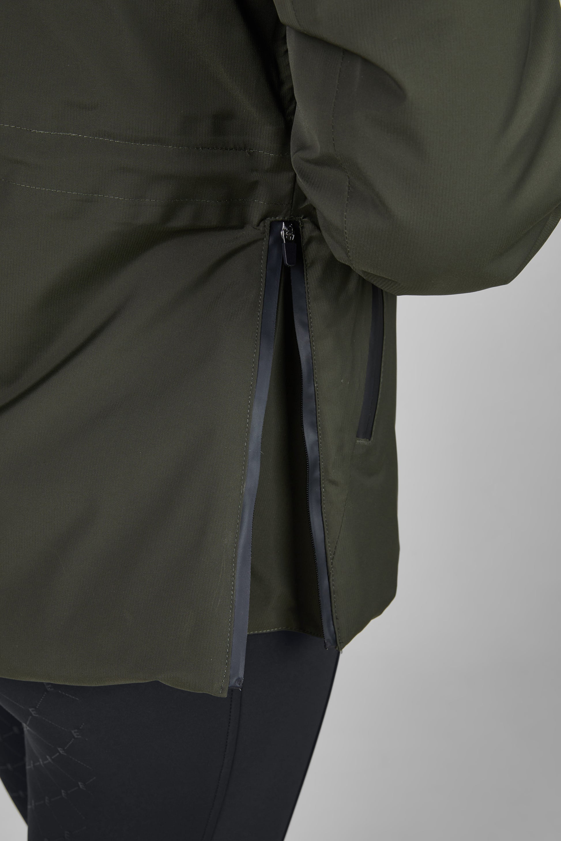 Close-up of a green jacket with a zipper on a light gray background