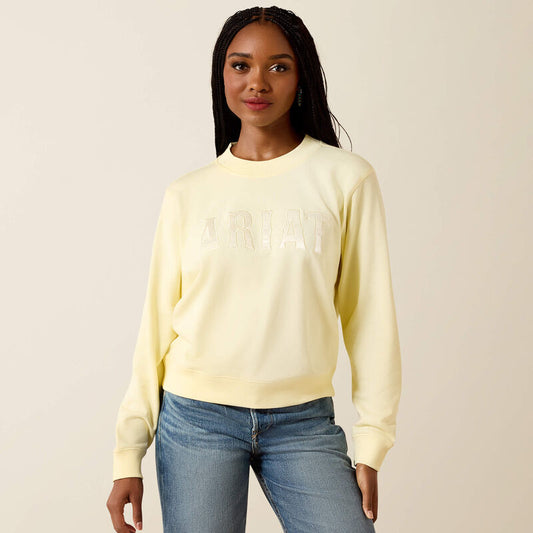 Woman wearing a light yellow sweatshirt and blue jeans on a beige background