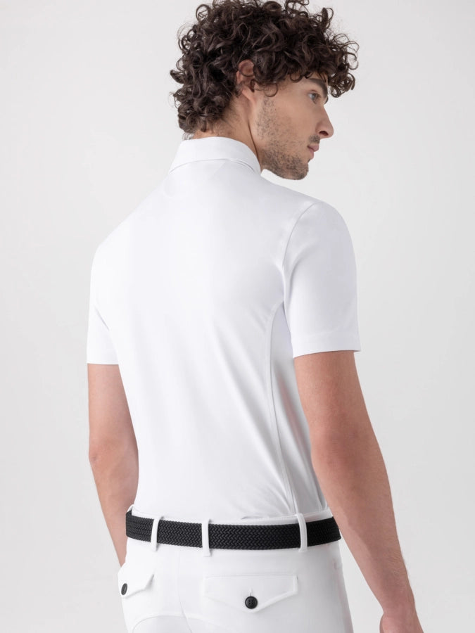 Man wearing a white polo shirt and white pants with a black belt on a light gray background