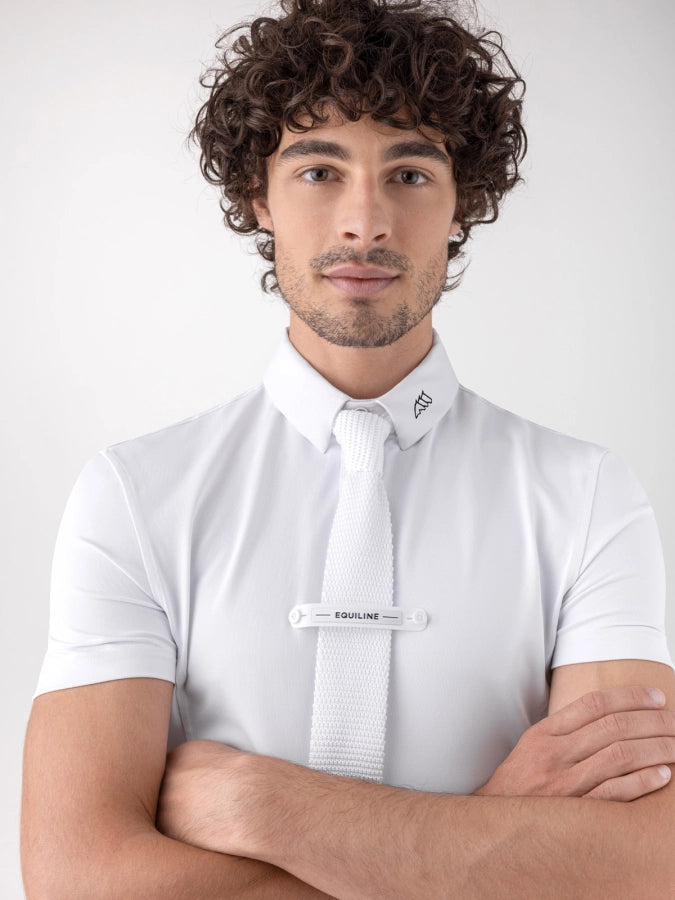 Man wearing a white shirt with a tie over it against a plain background