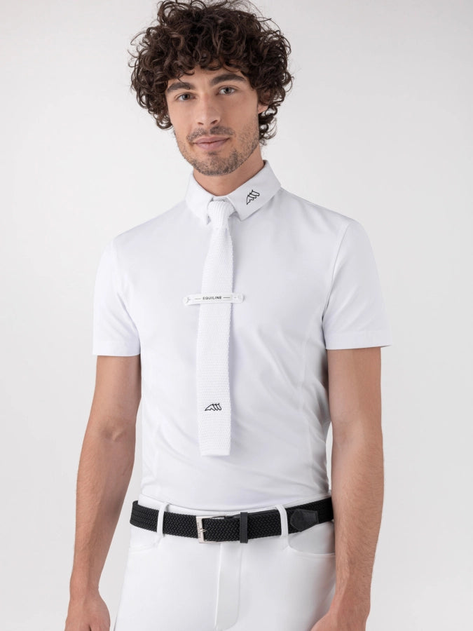 A man wearing a white short-sleeve dress shirt with a matching white tie and a black belt, photographed against a light gray studio background.