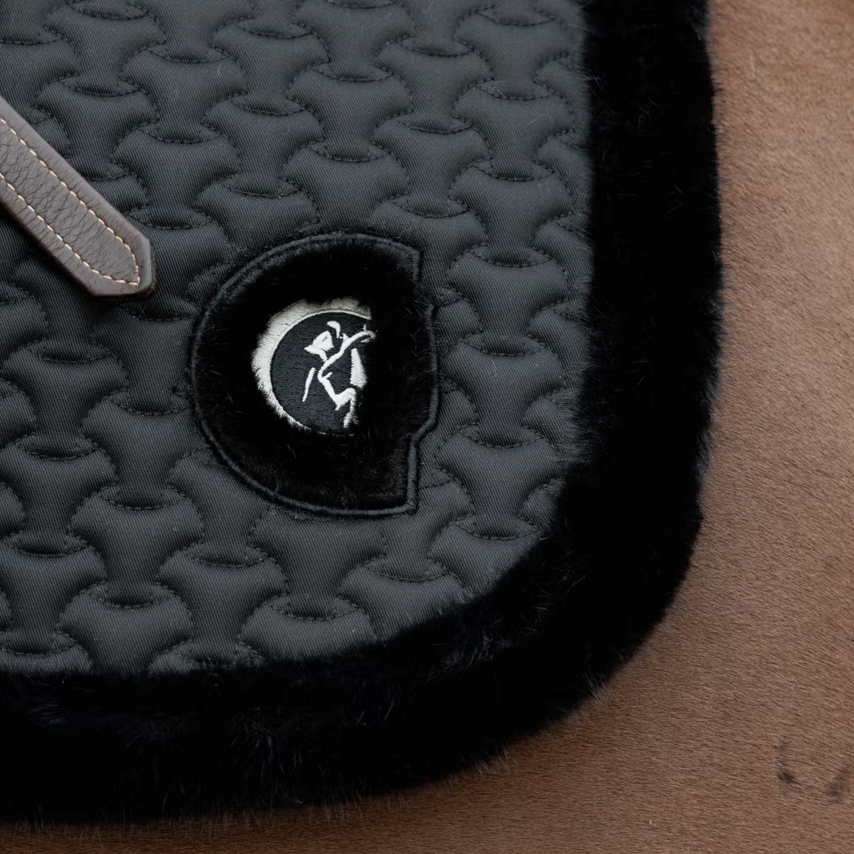Close-up of a textured black product with a logo on a brown surface