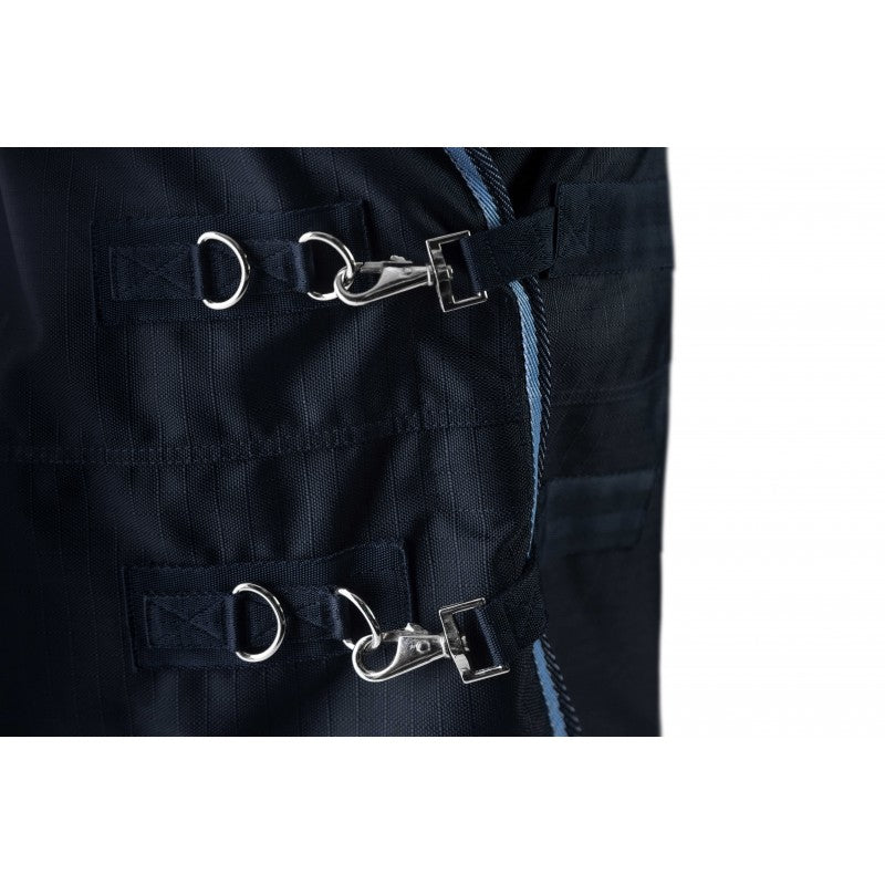 Close-up detail of dark navy blue fabric with multiple black straps, silver metal D-rings, and snap hooks, plus a light blue stitched edge on a white background.