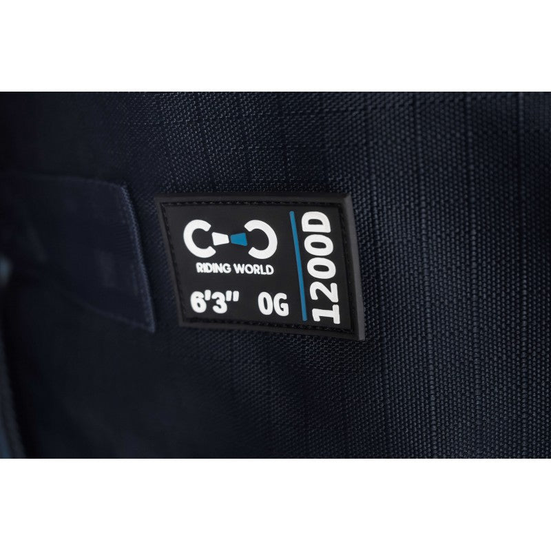 Close-up of a black rectangular brand patch sewn onto dark navy fabric, showing the Riding World logo and text including 1200D, 6'3" OG.