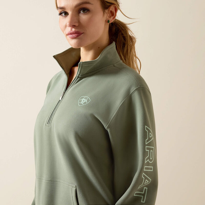 Woman wearing a green Ariat jacket on a beige background