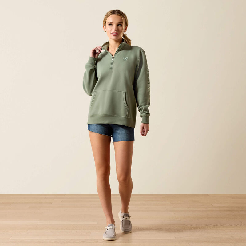 Woman wearing a green sweatshirt and denim shorts on a beige background