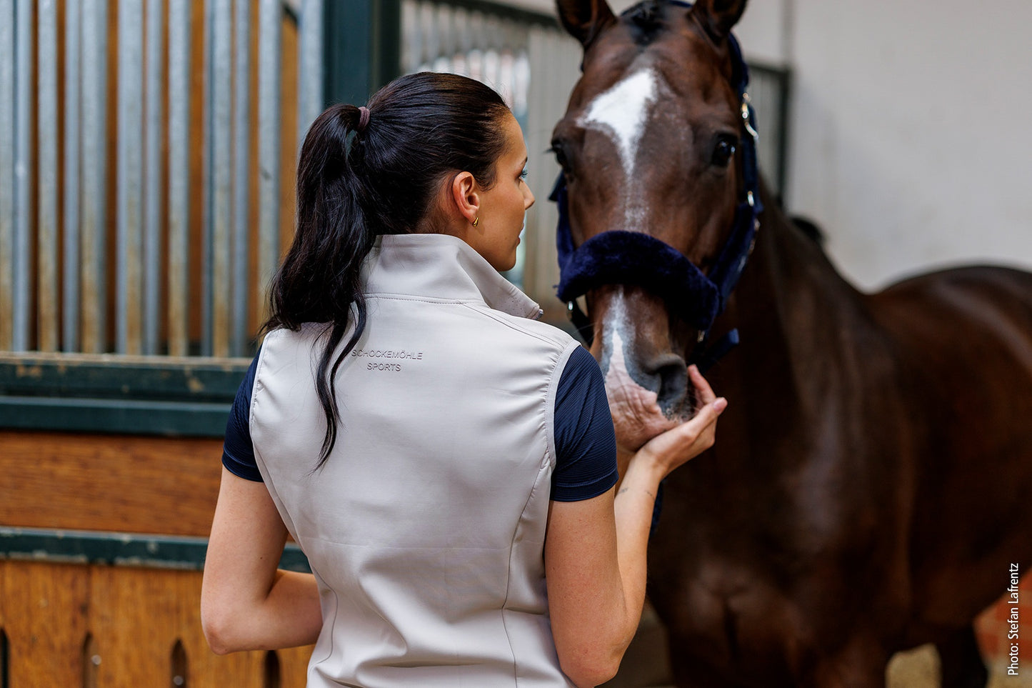 Woman petting a horse in an indoor stable