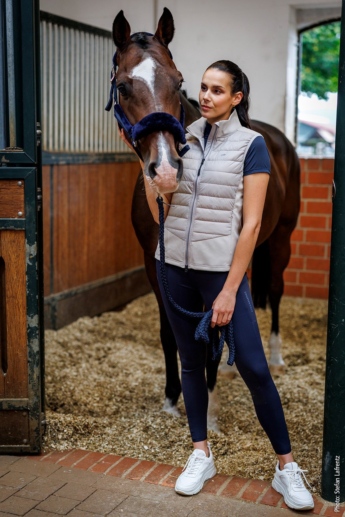 Woman standing next to a horse in a stable