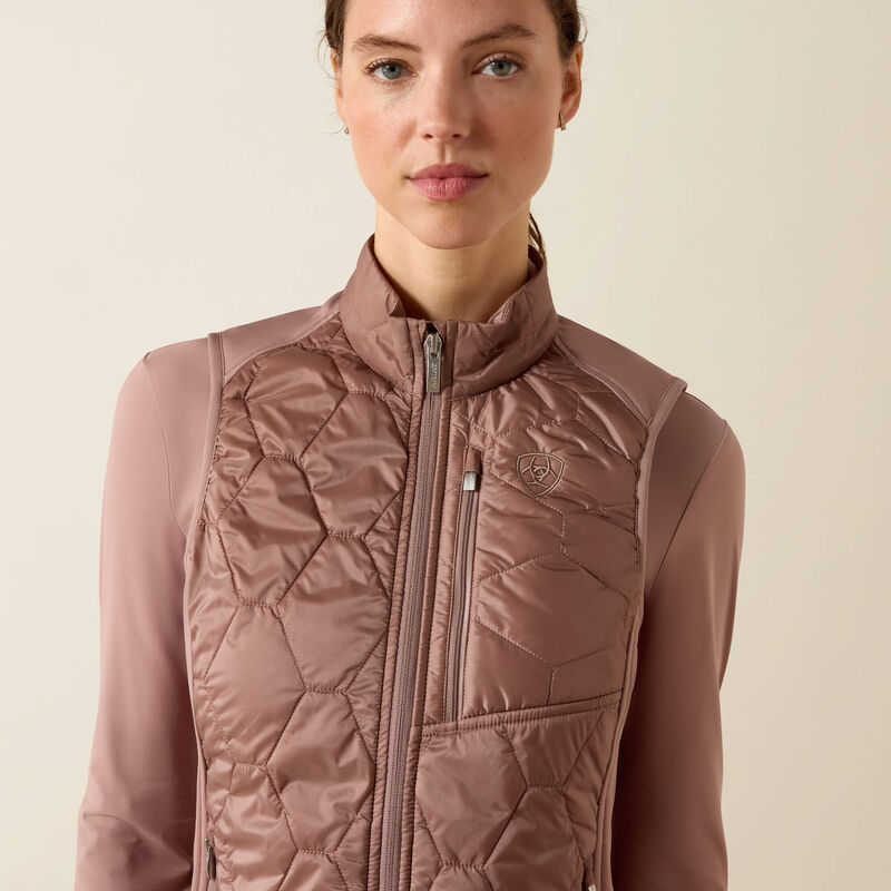 Woman wearing a quilted pink jacket against a beige background