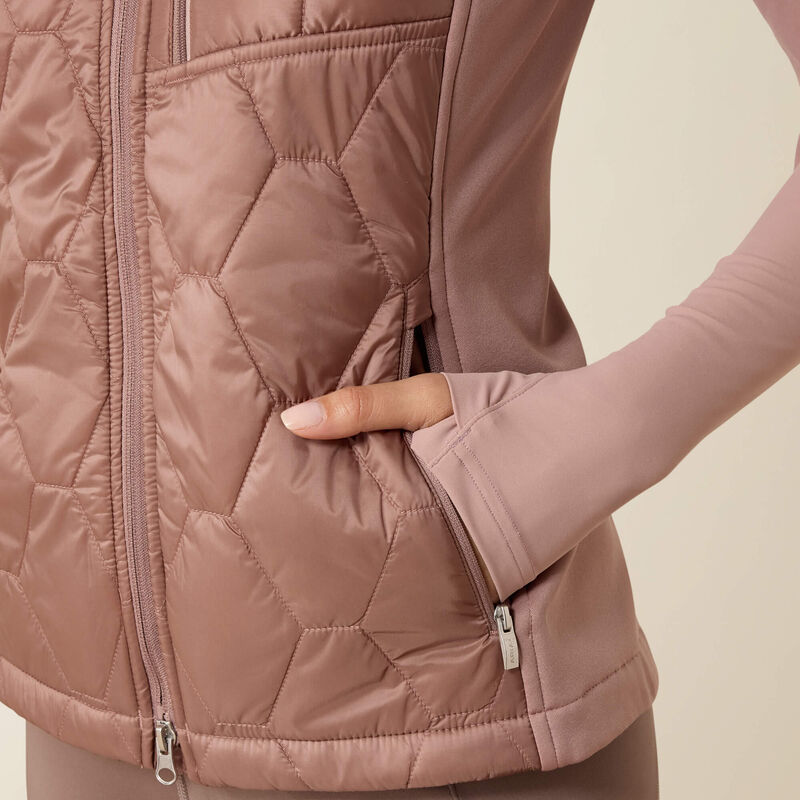 Close-up of a person wearing a quilted pink jacket on a beige background
