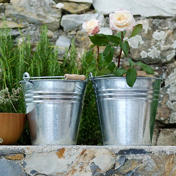 Two metal buckets with roses in them