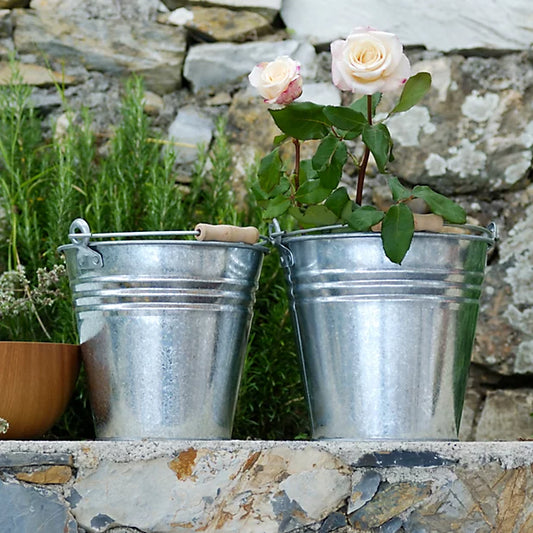 Two metal buckets with roses in them