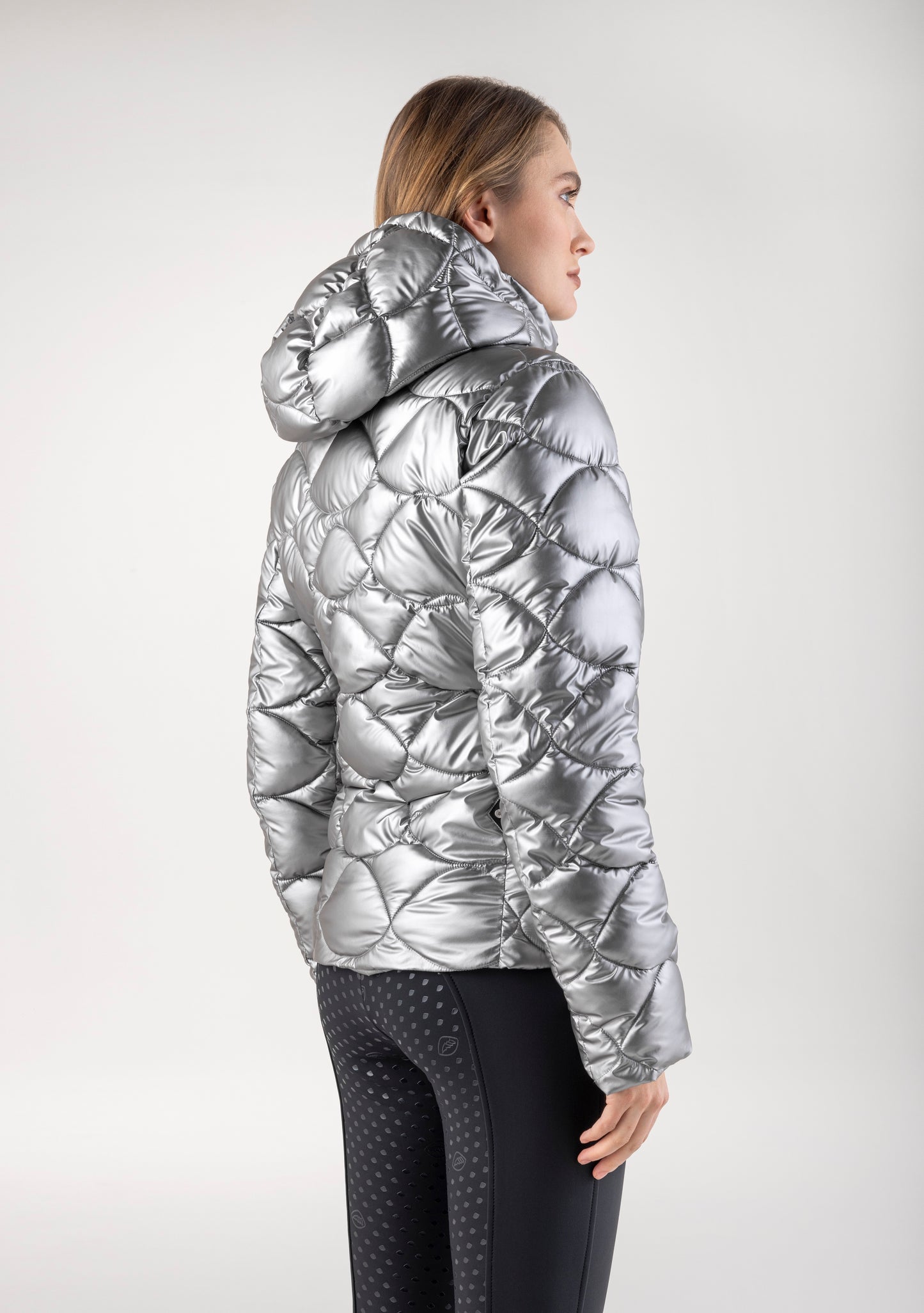 Person wearing a silver quilted jacket on a white background