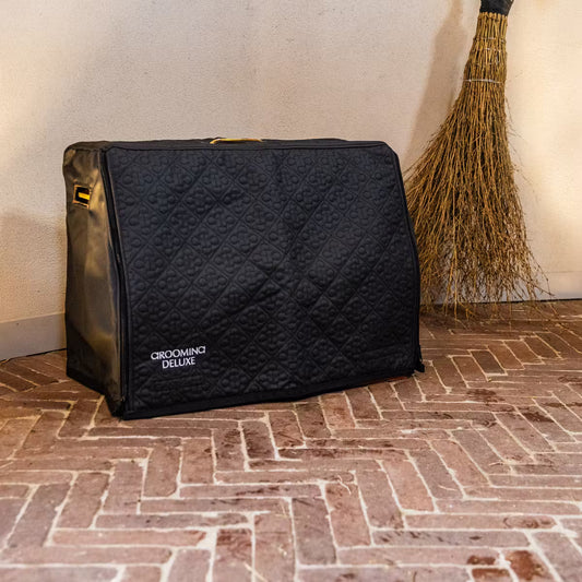 Black grooming bag with 'Grooming Deluxe' branding on a brick floor.