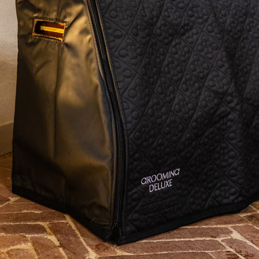 Black grooming bag with 'Grooming Deluxe' branding on a brick floor.