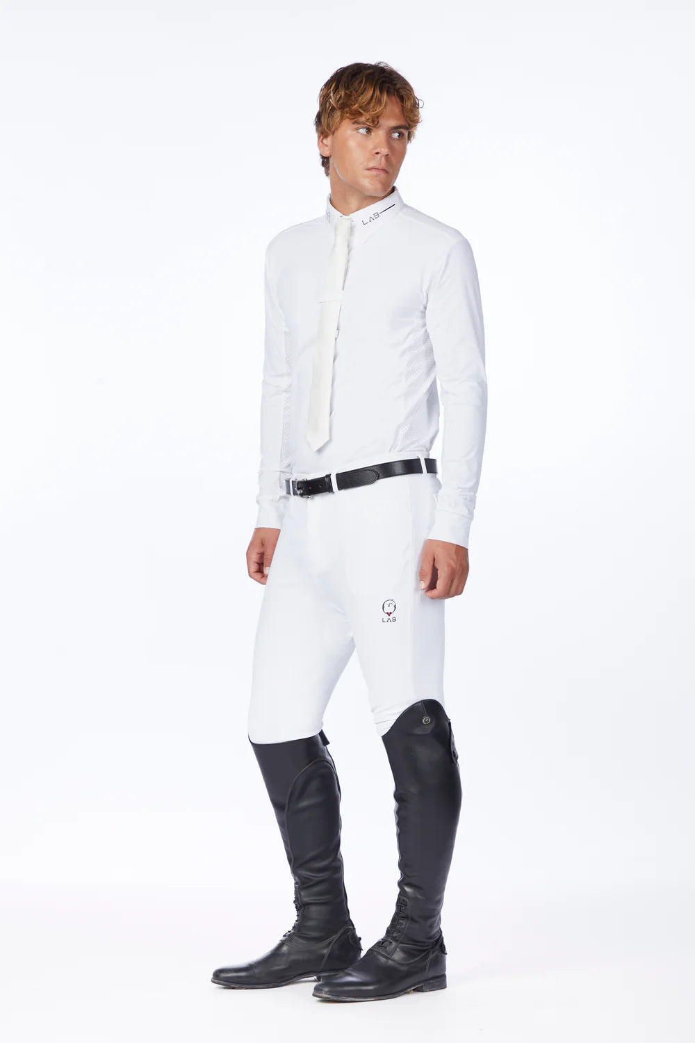 Man wearing a white equestrian jacket and black riding boots on a white background
