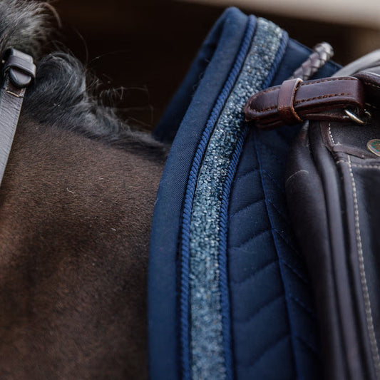 Glittery navy saddle pad under a brown saddle 