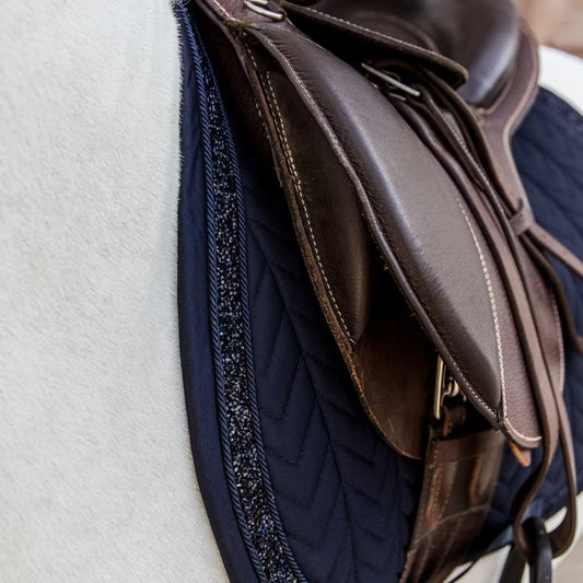 Glittery saddle pad on a horse under a brown saddle