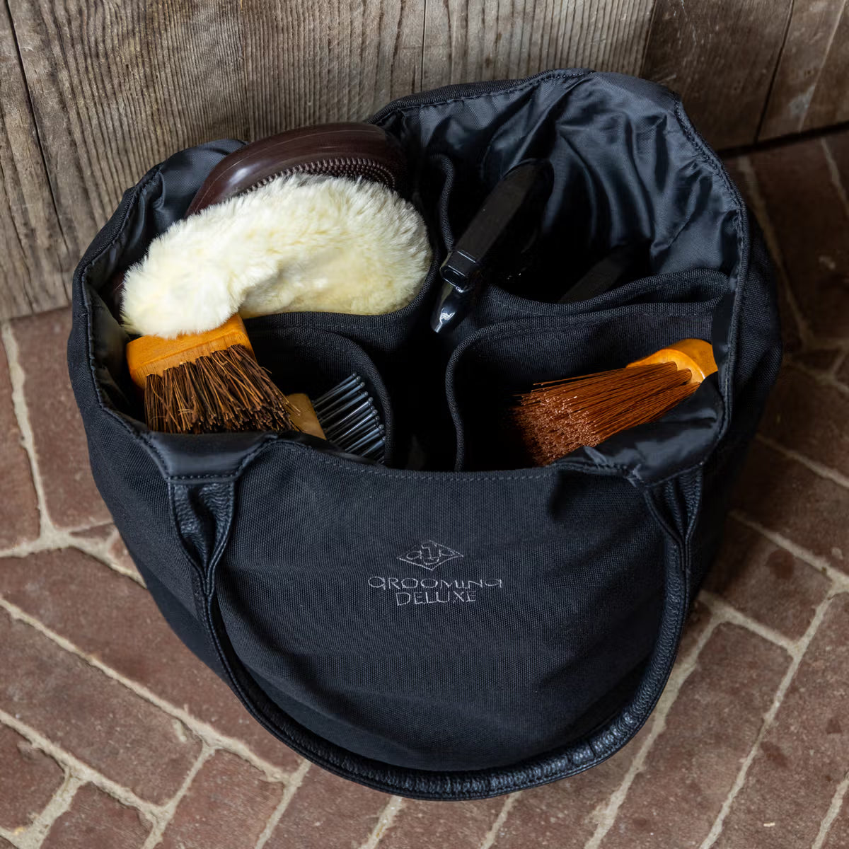 Black grooming bag full of grooming brushes and Grooming Deluxe branding.