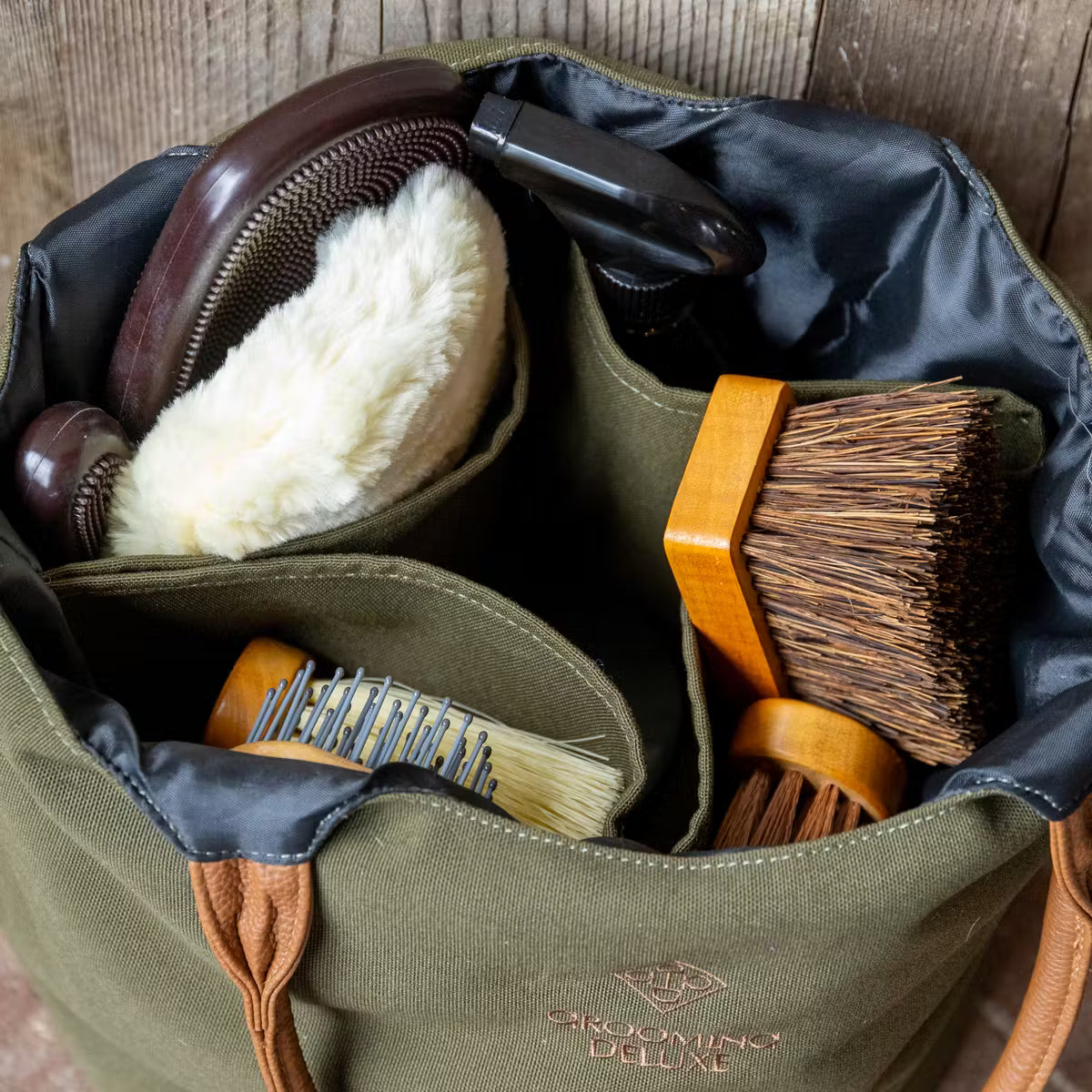 Green grooming bag with brushes and tools on a wooden surface