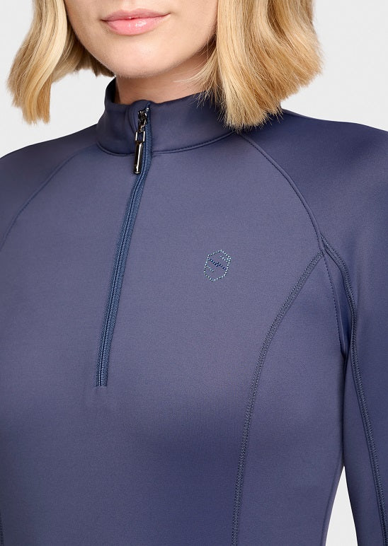 Close-up of a model wearing a navy blue long-sleeve quarter-zip top with a small geometric logo on the left chest, set against a plain light gray background.