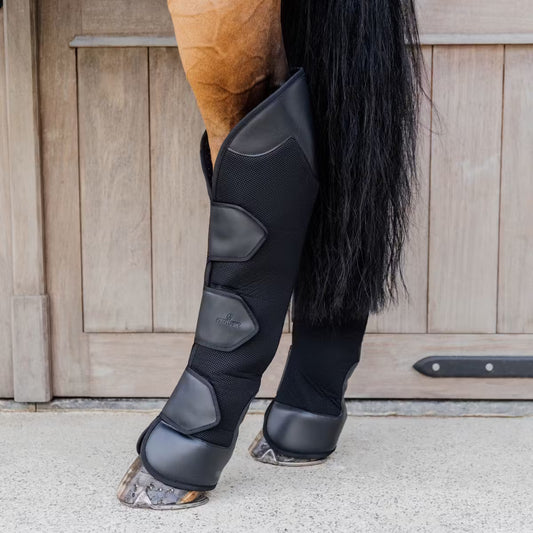 Horse leg with protective black leg wraps against a wooden fence background