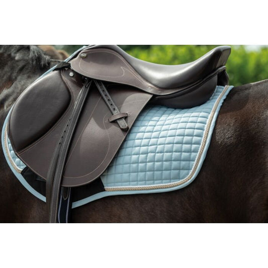 Horse saddle with a light blue quilted pad on a horse.