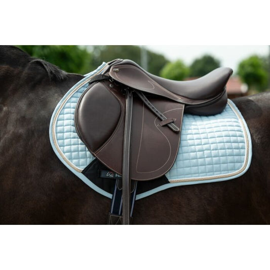 Brown saddle on a horse with a light blue quilted pad