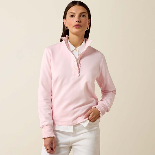 Woman wearing a pink quarter-zip sweater over a white shirt on a beige background