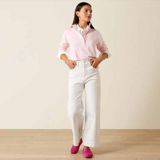 Woman wearing a pink shirt, white pants, and pink shoes on a plain background