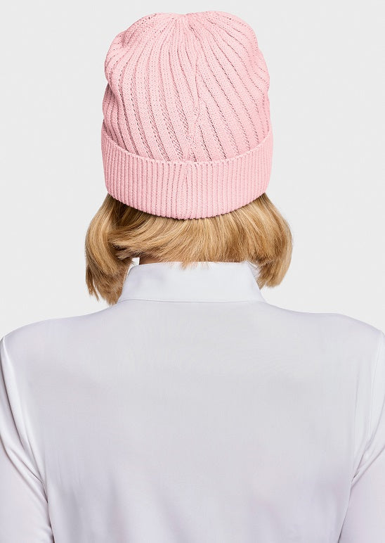 A person shown from the back wearing a light pink ribbed knit beanie and a white high-neck top against a plain light gray studio background.