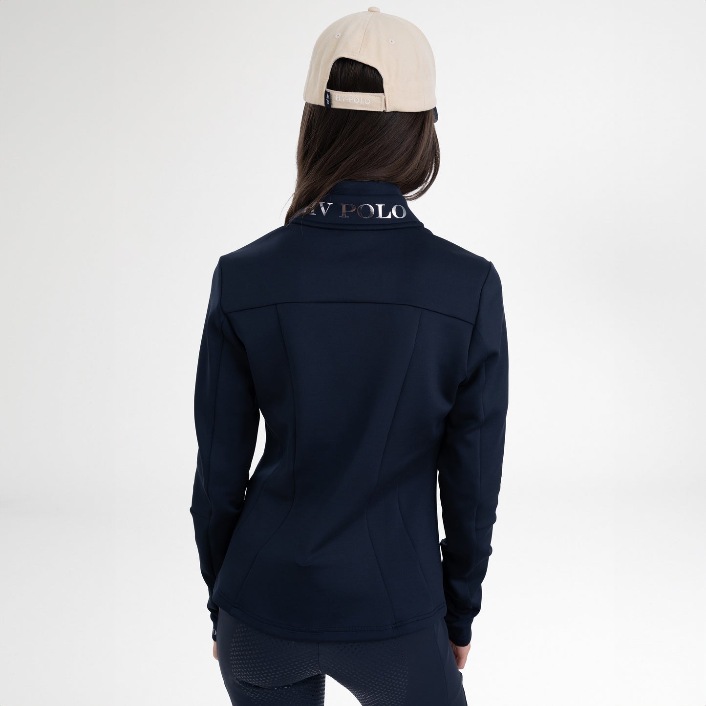 Girl wearing a navy full zip sweatshirt, a pair of navy tights and a navy and beige baseball cap on a white background