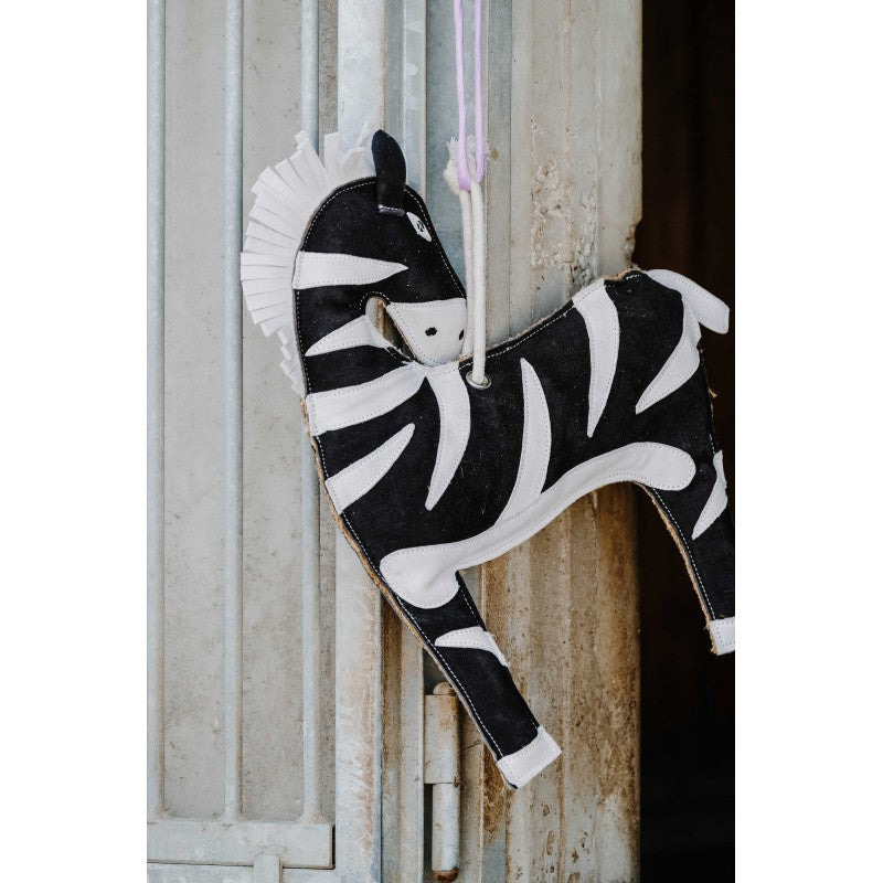 Zebra-shaped toy hanging against a rustic wooden background