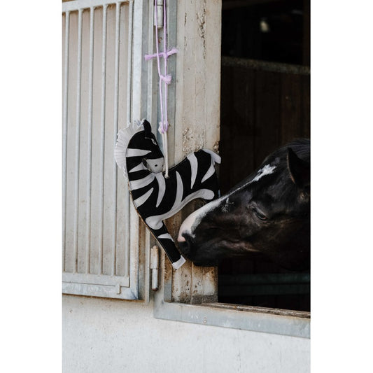 Horse interacting with a zebra-striped toy in a stable.